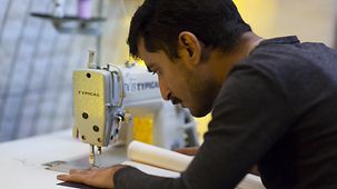 Abid Ali arbeitet an einer Nähmaschine mit einem Teilstück eines ehmaligen Schlauchbootes. 