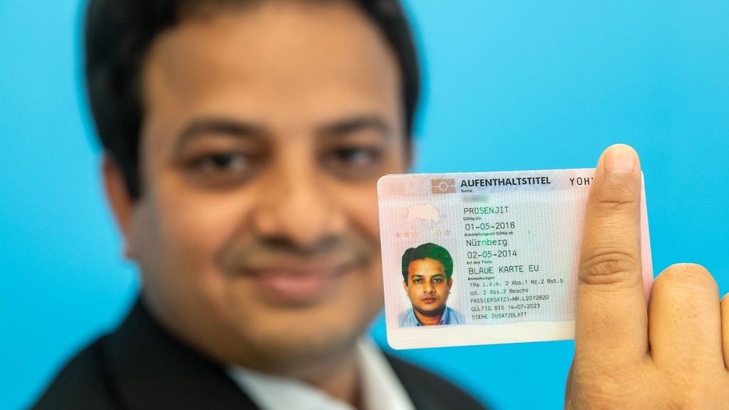 An Indian IT expert holds up his EU Blue Card.