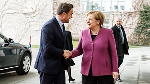 Chancellor Angela Merkel greets Luxembourg's Prime Minister and Minister of State Xavier Bettel.