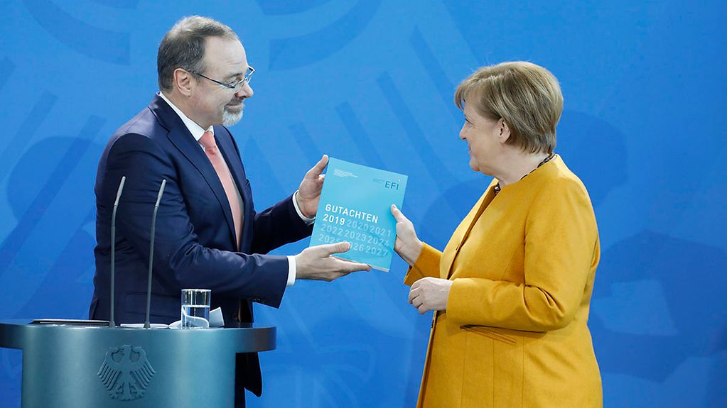 Chancellor Angela Merkel is presented with the report produced by the Commission of Experts for Research and Innovation (EFI) at the Federal Chancellery.