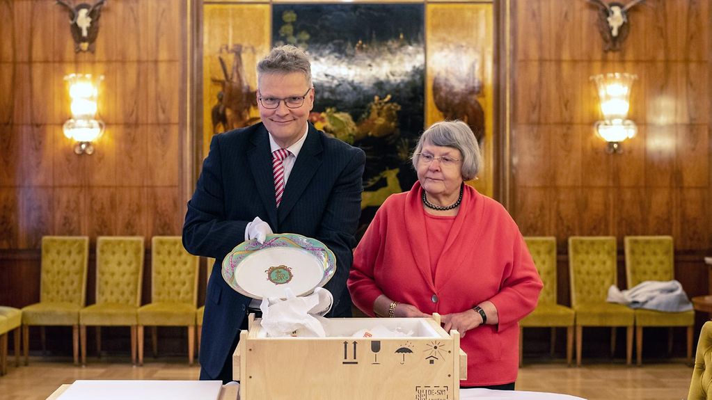 Ortwin und Friedgard Dally übergeben einen Porzellanteller in der Russischen Botschaft in Berlin.