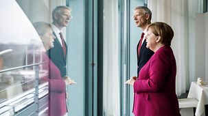 Chancellor Angela Merkel and Latvian President Krišjānis Kariņš stand at a window.