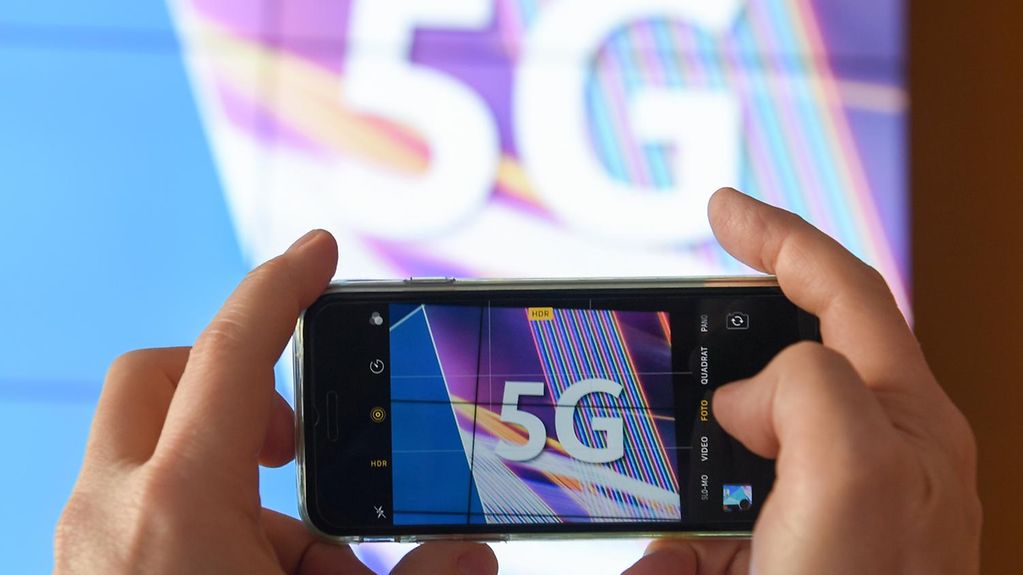 Before the start of the auction of the 5G spectrum bands a journalist takes a photo of the 5G acronym with a smartphone at the Bundesnetzagentur in Mainz.