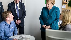Chancellor Angela Merkel talks to staff at the job centre.