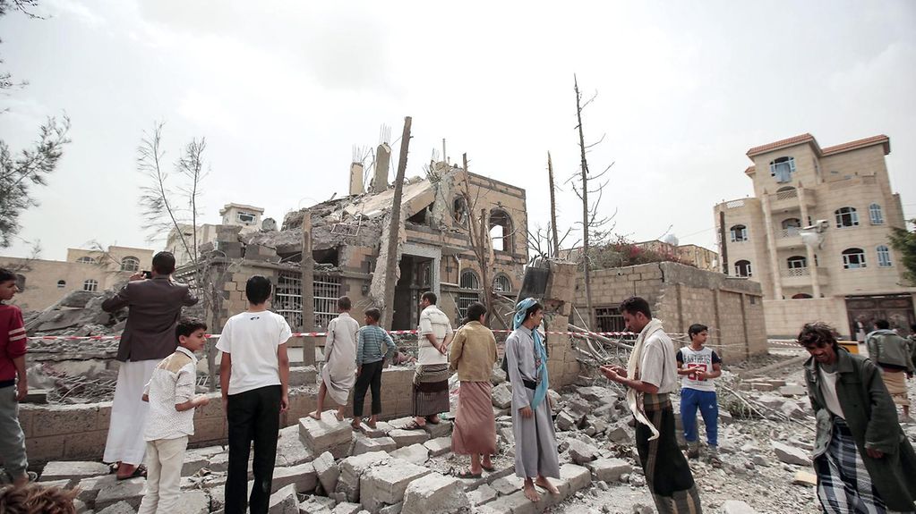 Des habitants regardent les décombres d’une maison endommagée lors d’un raid aérien de la coalition militaire conduite par l’Arabie saoudite