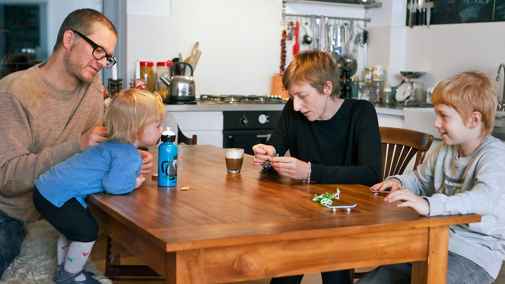 ein Vater spielt mit seinen drei Kindern am Tisch