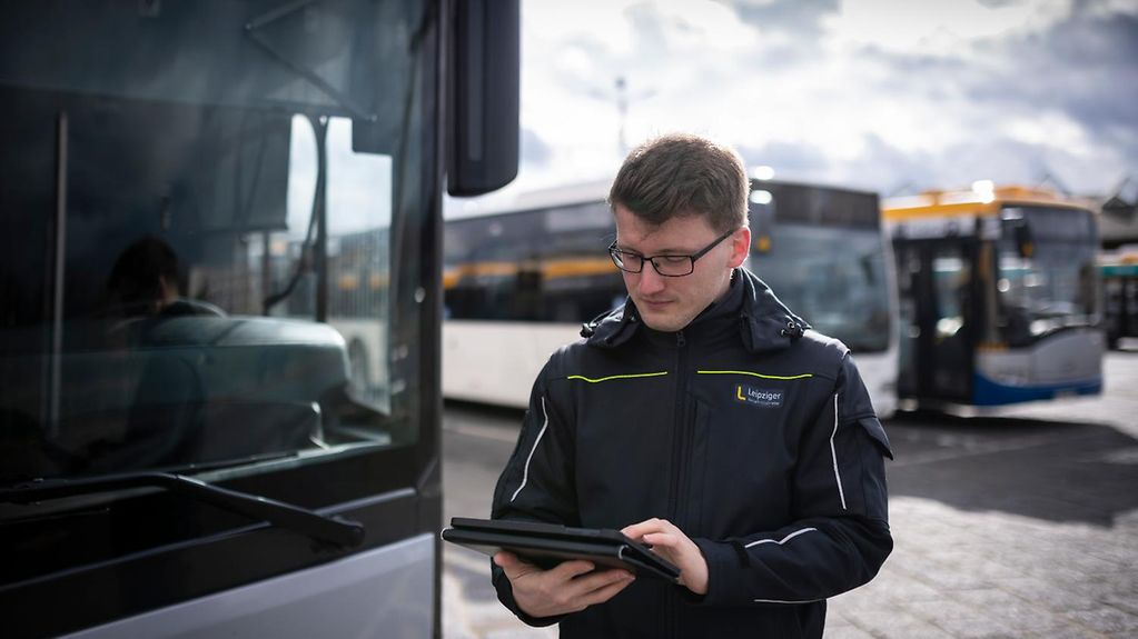 Ein Leipziger Busfahrer schaut auf sein Tablet.