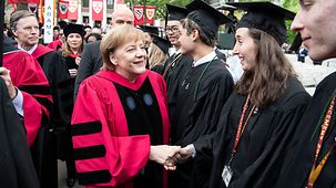 Bundeskanzlerin Angela Merkel gibt bei den Graduiertenfeierlichkeiten der Univeristät von Harvard einer Absolvrentin die Hand.
