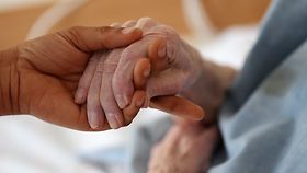 Eine Pflegerin hält im Caritas-Altenheim in Köln die Hand einer Bewohnerin.