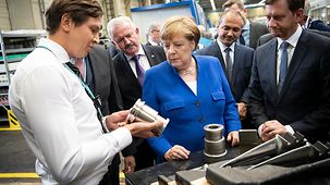 An employee of the Siemens turbine plant explains to the Chancellor how the steam turbines are produced.