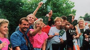 Glückliche DDR-Flüchtlinge winken mit ihren Reisepässen