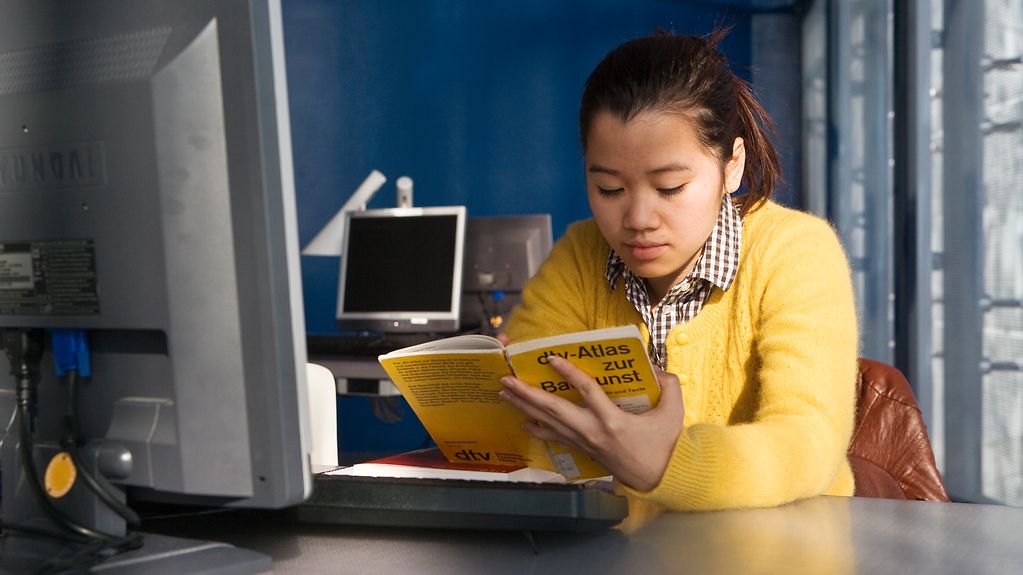 Eine Studentin aus China arbeitet in einer Bibliothek.