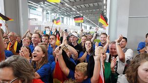 Eine Menschentraube, die jubelnd Deutschlandflaggen schwingt, klatscht und lacht. 
