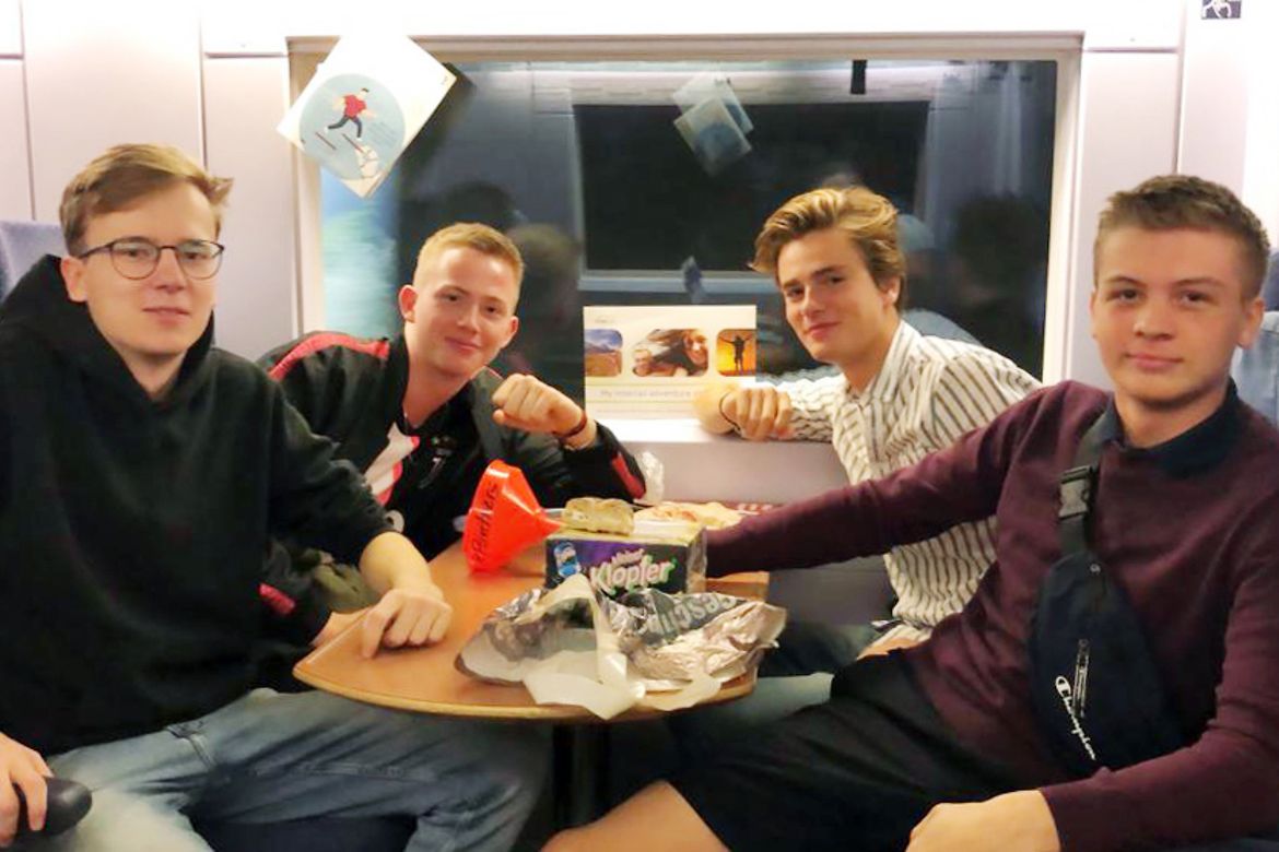 Vier junge Männer in einem Zugabteil