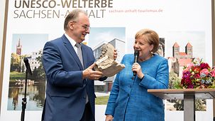 Reiner Haseloff, Sachsen-Anhalts Ministerpräsident, schenkt Angela Merkel ein Originalstück aus dem Naumburger Dom.