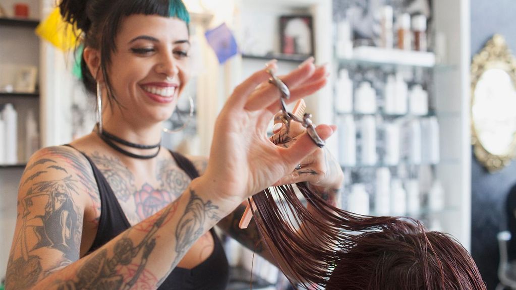 A hairdresser cuts a customer's hair.