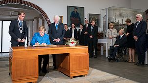 Bundeskanzlerin Angela Merkel trägt sich in das Gästebuch von Kiel ein.