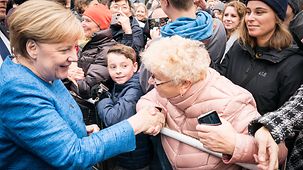 Bundeskanzlerin Angela Merkel schüttelt die Hand einer älteren Frau.