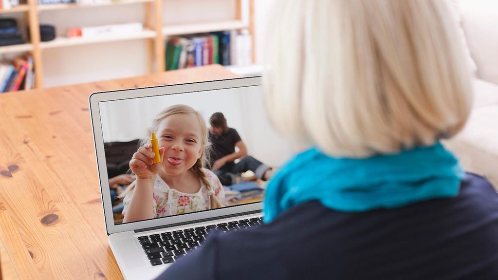Eine Frau telefoniert über Skype mit einem kleinen Mädchen, das sie auf dem Laptop sieht