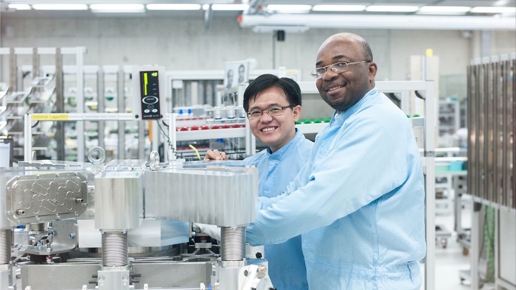 Zwei ausländische Arbeitnehmer bei einer Lasermontage