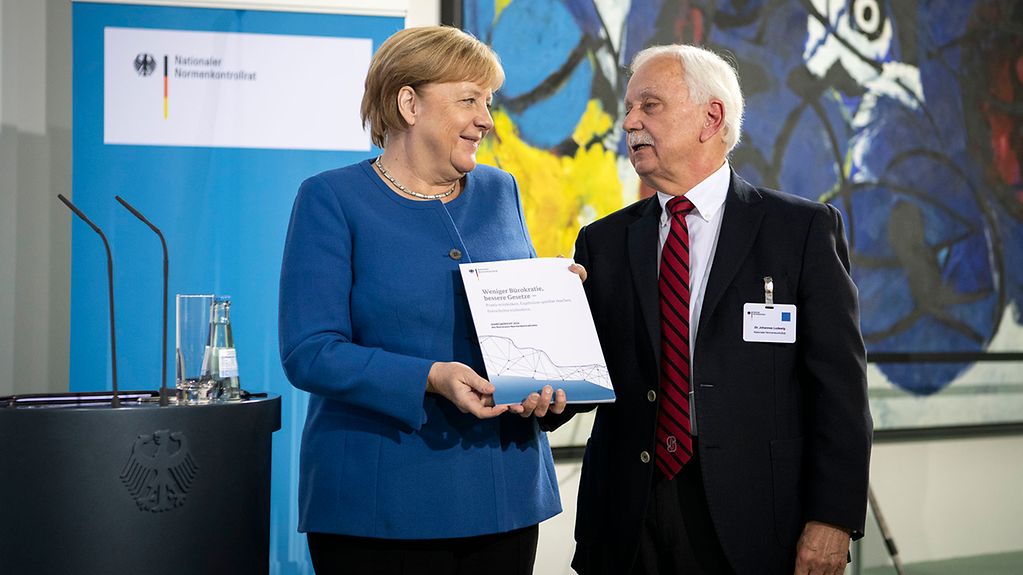 Bundeskanzlerin Angela Merkel bekommt von Johannes Ludewig, Vorsitzender des Normenkontrollrats den Jahresbericht überreicht.