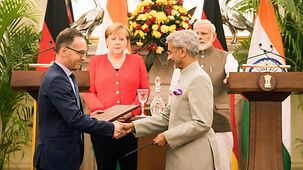 Bundeskanzlerin Angela Merkel verfolgt eine Unterzeichnung bei den Deutsch-Indischen Regierungskonsultationen.