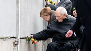 Bundeskanzlerin Merkel und Bundesratspräsident Schäuble stecken Rosen in die Mauer bei der Zentralen Gedenkveranstaltung der Stiftung Berliner Mauer an der Gedenkstätte Berliner Mauer.
