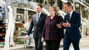 During a tour of the Volkswagen plant, Chancellor Angela Merkel walks between Saxony's state premier Michael Kretschmer and Volkswagen CEO Herbert Diess.