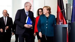 Chancellor Angela Merkel walks beside Christoph Schmidt, Chairman of the German Council of Economic Experts.