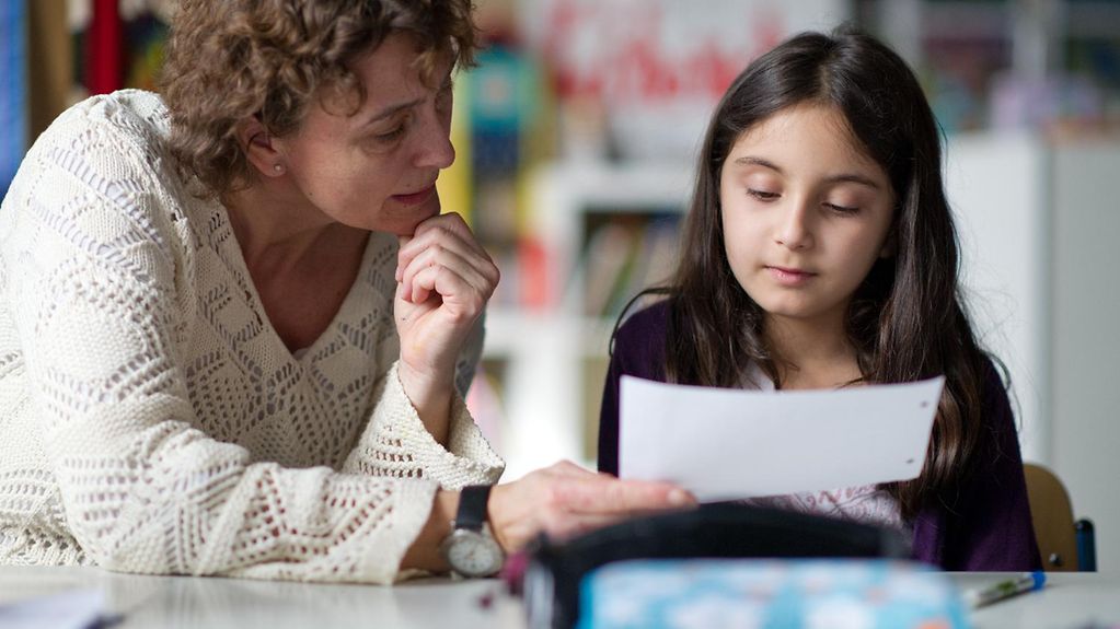 Une éducatrice et une enfant regardent une feuille de papier