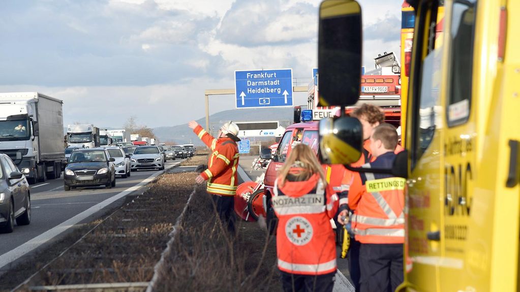 Emergency services at the scene of a motorway accident. One officer waves at traffic on the opposite carriageway to move on.