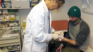 Ärztin Herbst-Oehme verbindet die Hand des Patienten.