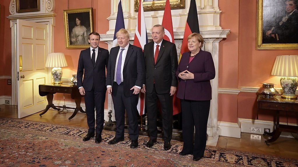 La chancelière allemande, le président français, le premier ministre britannique et le président turc devant des drapeaux