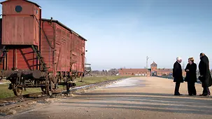 Die Kanzlerin steht neben einem alten Eisenbahnwaggon auf dem Gelände des ehemaligen Konzentrationslagers Auschwitz.
