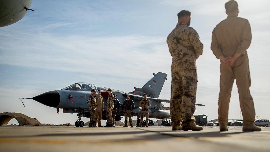 Bundeswehr soldiers stand beside a Tornado fighter jet