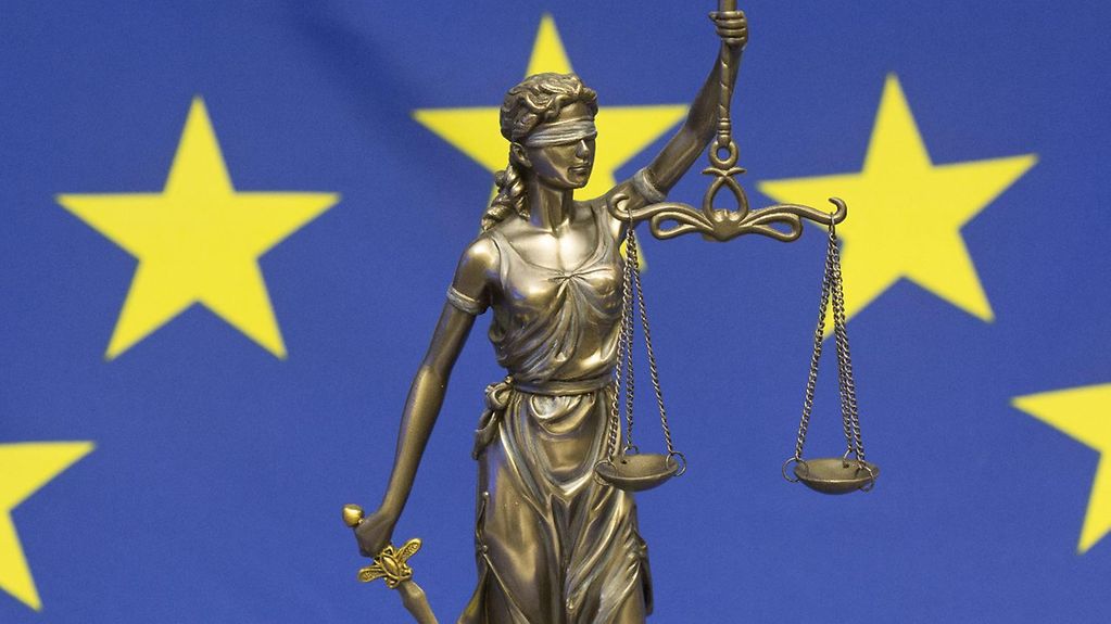  Bronze statue of the Roman goddess Justitia against the background of an EU flag
