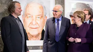 La chancelière fédérale Angela Merkel aux côtés de Naftali Fürst et de l’artiste Martin Schoeller lors de l’inauguration de l’exposition « Survivors »