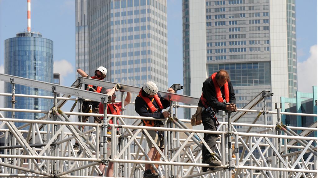 Workers put up scaffolding for a stage on the banks of the River Main in Frankfurt am Main.