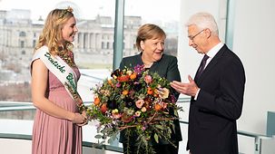 Chancellor Angela Merkel is presented with a bouquet.