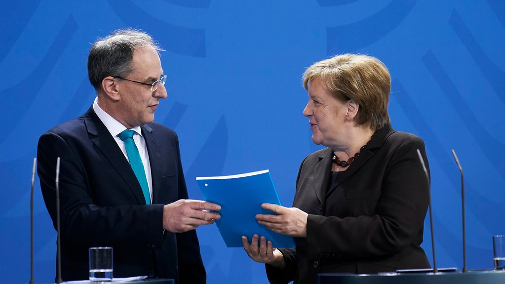Uwe Cantner, Chairman of the Commission of Experts for Research and Innovation, presents Chancellor Angela Merkel with the Commission's annual report.