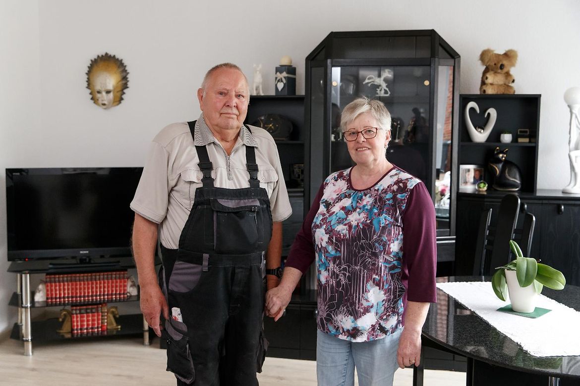 Karin und Horst Sickert stehen in ihrem seniorengerecht gestalteten Wohnzimmer vor einer Schrankwand