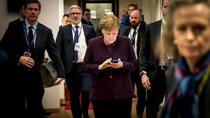 Bundeskanzlerin Angela Merkel schaut auf ihr Handy während sie zu einer Sitzung des Europäischen Rates geht.