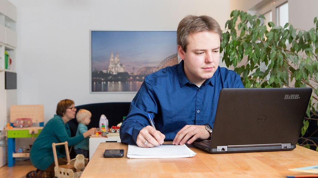 Ein Mann arbeitet zu Hause an seinem Esstisch am Laptop.