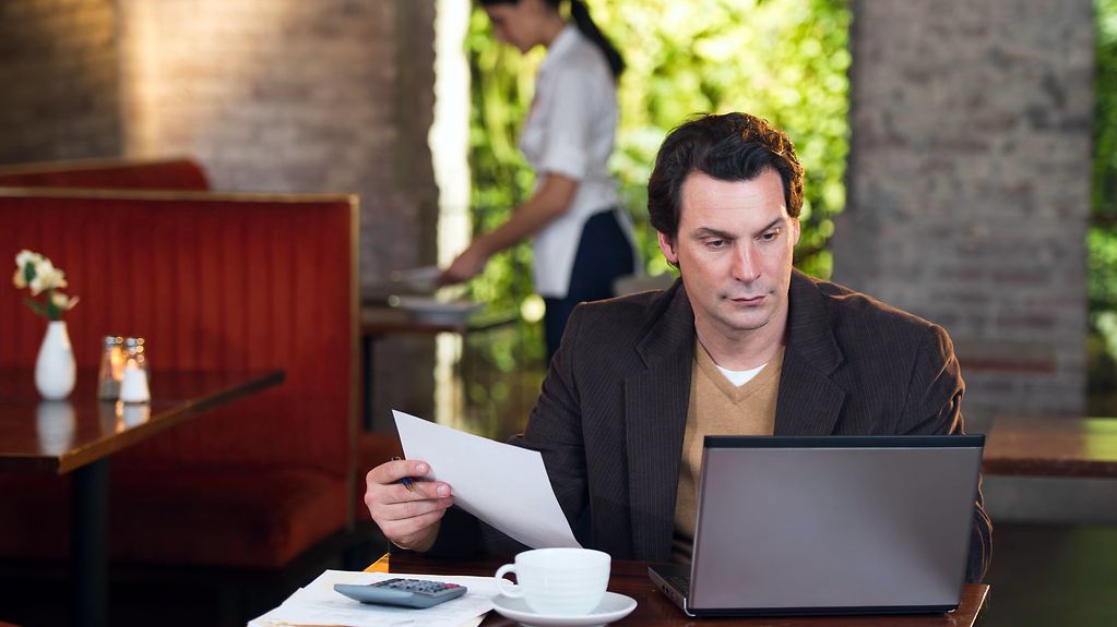 Ein Mann sitzt mit einem Laptop am Tisch