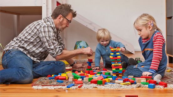 Ein Vater spielt im Kinderzimmer mit seinen zwei Kindern