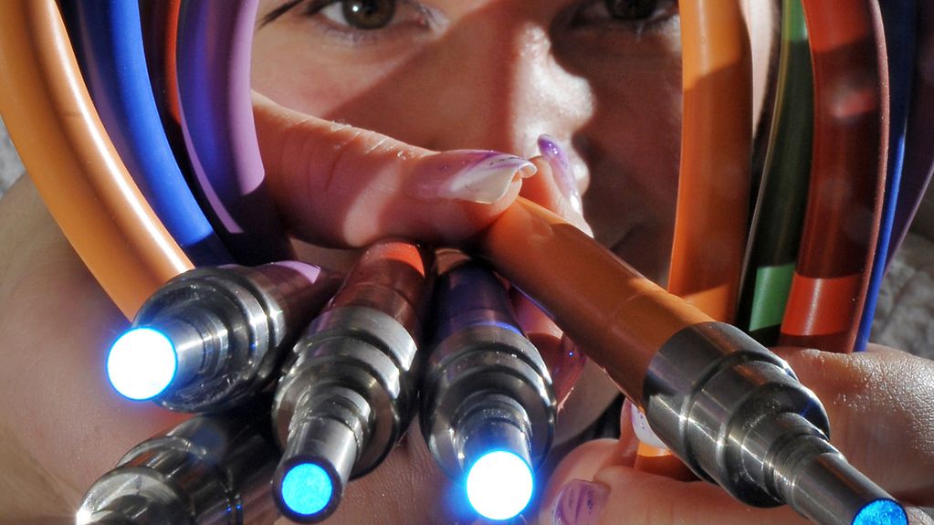 Eine Montagearbeiterin zeigt farbig ummantelte Kaltlichtkabel.
