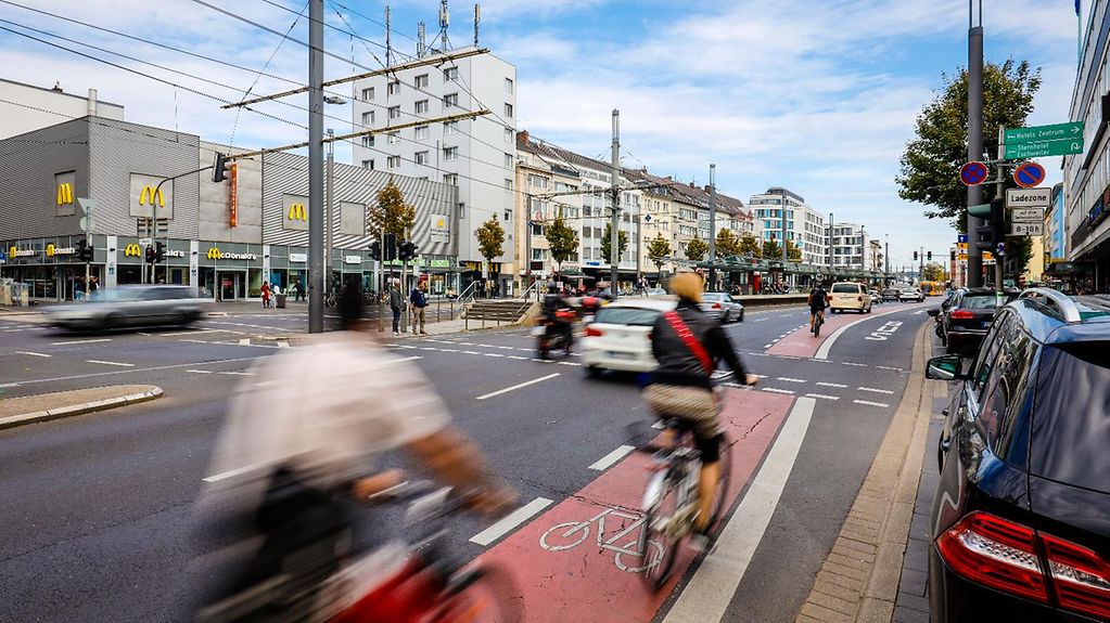 Eine Straßenkreuzung mit Fahrradfahrern auf dem roten Schutzstreifen für den Radverkehr. 