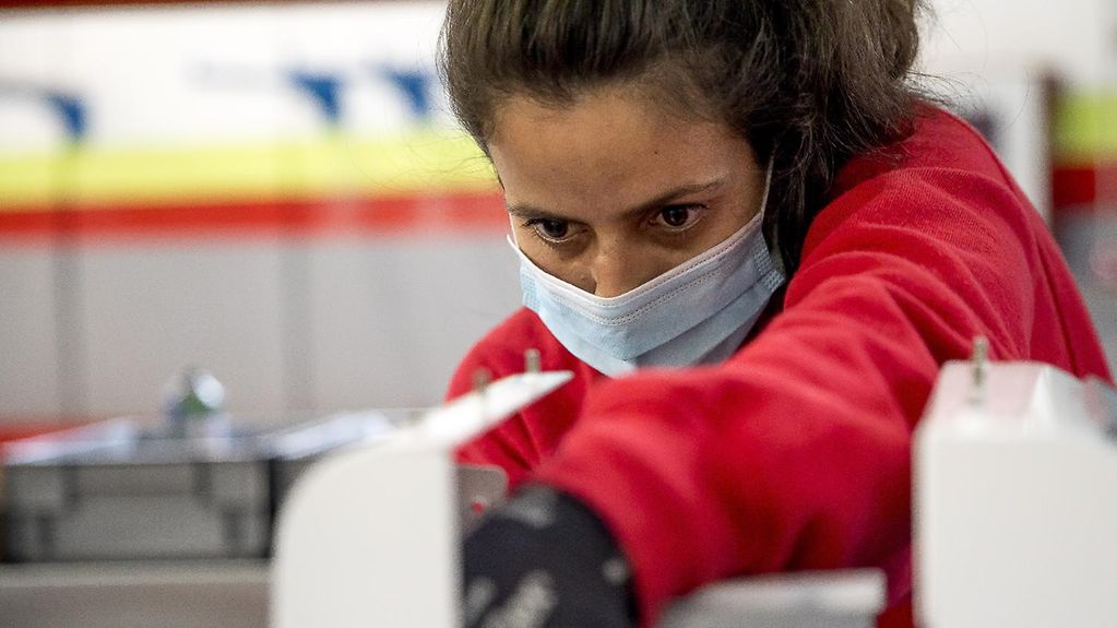 Eine Frau mit Schutzmaske arbeitet in einer medizinischen Produktion.