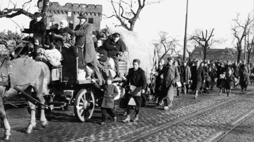 Ein historisches schwarz-weiß-Bild zeigt Menschen auf der Flucht.