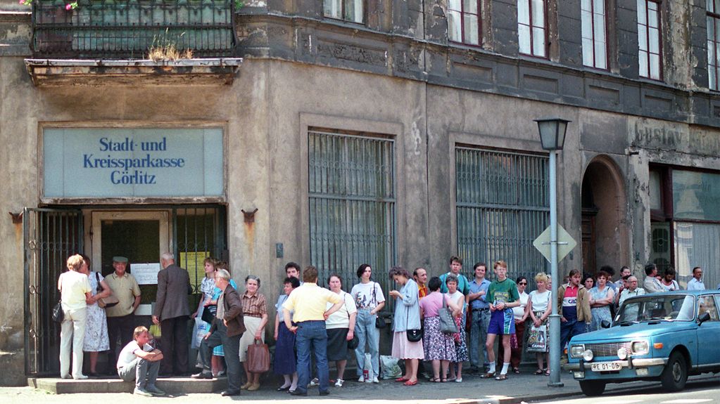Menschen stehen vor einem Gebäude an.